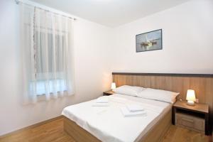 a bedroom with a bed with white sheets and a window at Apartments Maslina III in Njivice