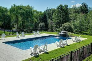 a swimming pool with chairs and a fountain at condo 3 chambres vue sur la montagne 837-202 in Bromont