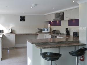 a kitchen with white cabinets and a counter with stools at Riverside in Bude