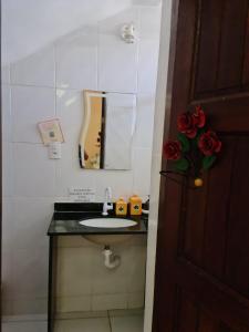 baño con lavabo, espejo y rosas rojas en Geribá Residence, en Búzios