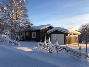 a building covered in snow with a fence in front at COZY COTTAGE-VILLA CLOSE TO WINTER SPORTS, MOUNTAIN & LAKE - 10 Pers in Mörsil