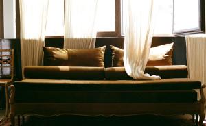 a couch sitting in front of a window with curtains at Mona Athens in Athens