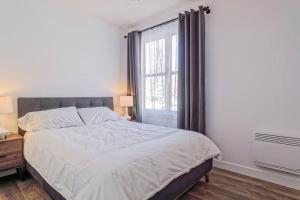 a bedroom with a large bed and a window at 201 Condo au rez de chaussée , au coeur de Bromont in Bromont