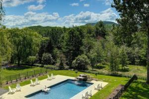 a backyard with a swimming pool and chairs and trees at 201 Condo au rez de chaussée , au coeur de Bromont in Bromont
