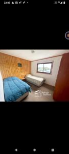 a bedroom with a blue bed and a window at REFUGIO GAMBOA in Castro