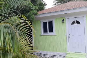 a green house with a white door and a window at Budget & Basic in Local Neighborhood, 7min Drive to Downtown Nassau Beach Paradise in Nassau