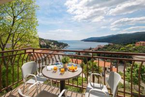 a table on a balcony with a view of the water at Apartment Rabac 19 in Rabac