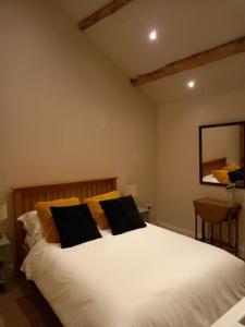 a bedroom with a white bed with two black pillows at Henry's Cottage in Skipton