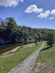 a dirt road in a field next to a river at Henry's Cottage in Skipton