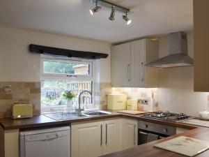 a kitchen with white cabinets and a sink and a window at Rose Cottage in Taxal