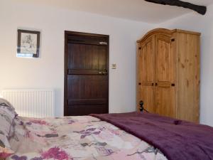 a bedroom with a bed and a wooden cabinet at Rose Cottage in Taxal