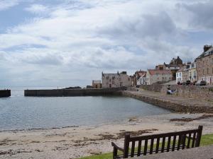 a bench sitting on the beach next to a body of water at Arc House in Cellardyke