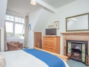 1 dormitorio con 1 cama y chimenea en The Coach House At Vane Hill en Torquay