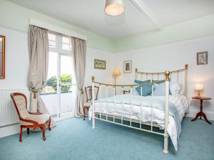 a bedroom with a bed and a chair and a window at The Coach House At Vane Hill in Torquay