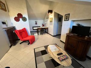 a living room with a red chair and a television at Appartamenti Papavero e Iris in Albaretto Della Torre 