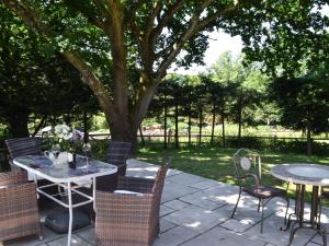 a patio with tables and chairs and a tree at Meadow Barn in Ellingham