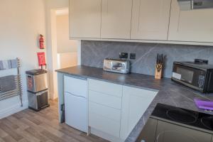 a kitchen with white cabinets and a microwave at Toothbrush Apartments - Ipswich East - Cauldwell Ave in Ipswich