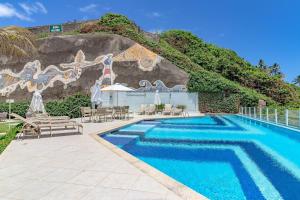 una piscina con sillas y sombrillas frente a una pared en RV05 Excelente Quarto e Sala, Pé na Areia - Rio Vermelho, en Salvador