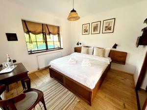 a bedroom with a bed and a desk and a window at Joyard - Pensiune & Parc in Porumbacu de Sus