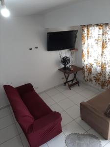 a living room with a red couch and a flat screen tv at Sobrado Em Matinhos Pr in Matinhos