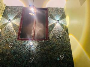 a bathroom with a mirror and lights on the wall at Kvm Tourist Home in Palakkad
