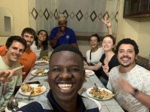 un grupo de personas sentadas alrededor de una mesa comiendo comida en JJ & JE Family House en Dar es Salaam