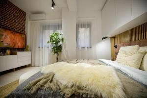 a bedroom with a large white bed with a furry rug at Modern Symphony - Stunning Central Apartment in Bucharest