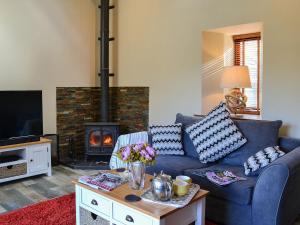 a living room with a blue couch and a fireplace at Garden Cottage in Coldingham