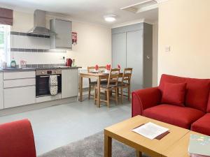 a living room with a red couch and a kitchen at Uk40237 - Beach Bank Bungalow in Lympne