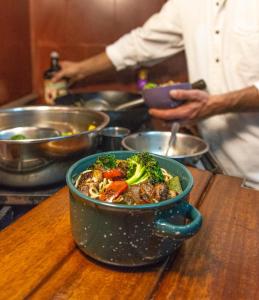 a bowl of food on a table with a person preparing food at KACLLA, The Healing Dog Hostel in Lima