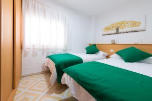 two beds in a room with green sheets at Piso Mirta Santa Cruz Tenerife in Santa Cruz de Tenerife