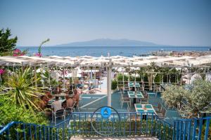 a restaurant with tables and white umbrellas on the beach at Majki Beach Apartments in Sarandë