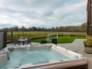a hot tub on a patio with a table and chairs at The Haybarn in Ferndown