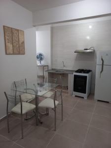 cocina con mesa de cristal, sillas y nevera en Apartamento living, en São Vicente