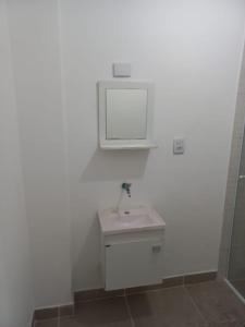 Baño blanco con lavabo y espejo en Apartamento living, en São Vicente