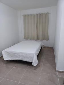 Habitación pequeña con cama y ventana en Apartamento living, en São Vicente