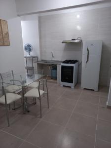 cocina con mesa, sillas y nevera en Apartamento living, en São Vicente