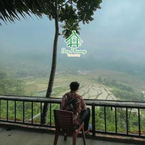 Un uomo seduto su una sedia che guarda verso una valle di Pu Luong - Duy Phuong Homestay a Thanh Hóa