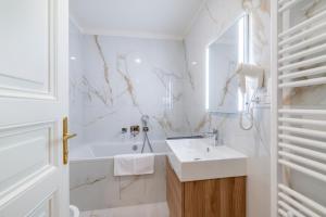 a white bathroom with a sink and a tub at Petrin Tower Residence in Prague +218 photos