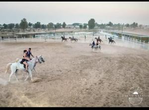 a group of people riding horses on a track at مزرعة دريم للتأجير 
