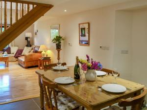 a dining room with a wooden table with flowers on it at Clematis Cottage in Holsworthy
