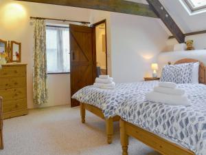 a bedroom with a bed and a dresser and a window at Clematis Cottage in Holsworthy