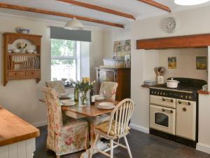 a kitchen with a table and chairs and a stove at Greenwood Cottage in Longframlington