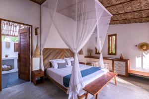 a bedroom with a bed with a mosquito net at Muita Paz in Atins