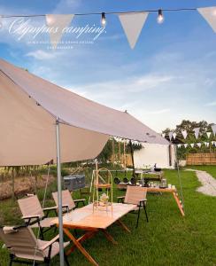 a picnic table and chairs under a large umbrella at Olympus camping-โอลิมปัสแคมป์ปิ้ง 