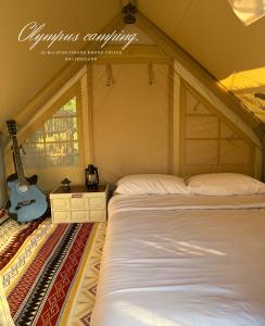 a bedroom with a bed and a guitar next to a window at Olympus camping-โอลิมปัสแคมป์ปิ้ง 