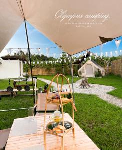 a table under an umbrella with a tray of food at Olympus camping-โอลิมปัสแคมป์ปิ้ง 