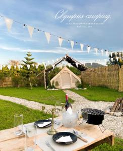 a picnic table with a bottle of wine and glasses at Olympus camping-โอลิมปัสแคมป์ปิ้ง 