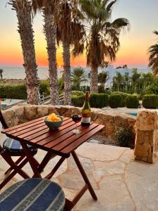een houten tafel met een fruitschaal en een fles wijn bij Sky Villa in Paphos City