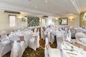 マンチェスターにあるHoliday Inn - Manchester - Oldham, an IHG Hotelの白いテーブルと椅子が備わる部屋での結婚式用のセットアップ